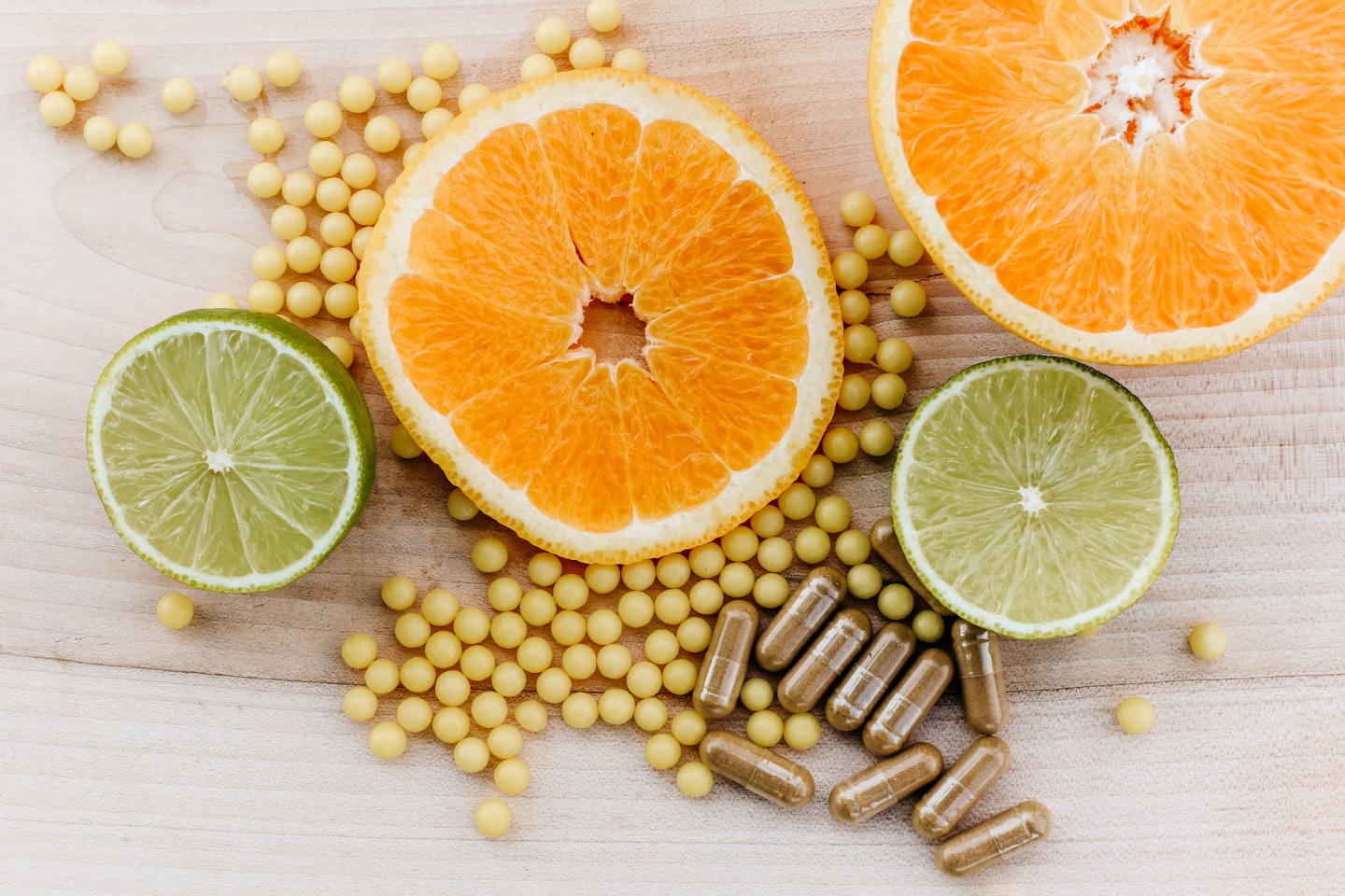 Citrus fruits and health supplements scattered on wood.